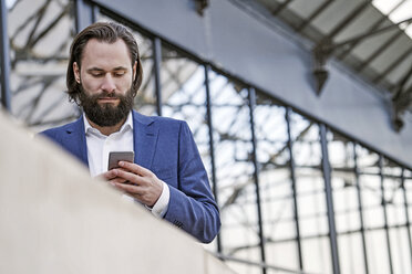 Geschäftsmann überprüft Mobiltelefon - FMKF03554