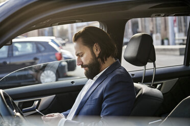 Businessman using cell phone in a car - FMKF03558