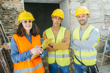 Woman with two construction workers on construction site - KIJF01243