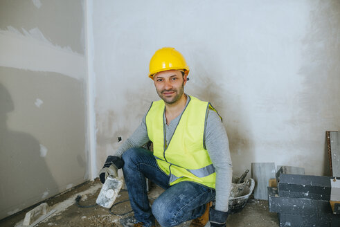 Porträt eines Bauarbeiters, der einen Hammer hält - KIJF01257