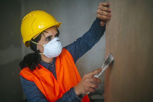 Frau auf der Baustelle beim Nivellieren der Wand - KIJF01262