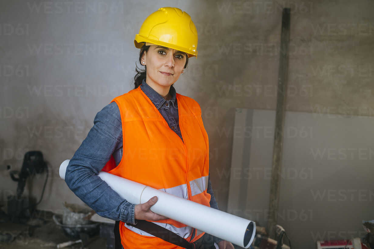Frau mit Schutzhelm und reflektierender Weste auf Baustelle mit
