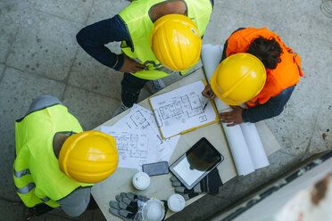 Woman and two men in workwear discussing construction plan - KIJF01268