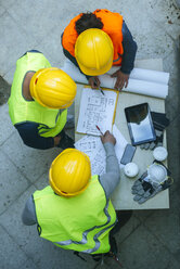 Frau und zwei Männer in Arbeitskleidung besprechen einen Bauplan - KIJF01269
