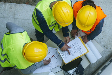 Woman and two men in workwear discussing construction plan - KIJF01270