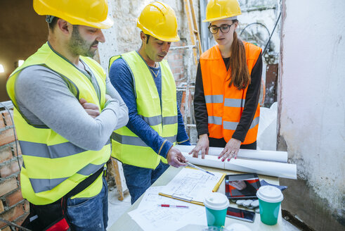 Frau und zwei Bauarbeiter unterhalten sich auf einer Baustelle - KIJF01275