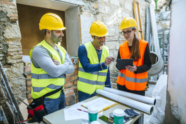 Frau und zwei Bauarbeiter mit Tablet auf einer Baustelle - KIJF01276