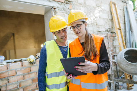 Woman with tablet talking to construction worker on construction site stock photo