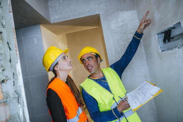 Bauarbeiter zeigt einer Frau die Elektroinstallation - KIJF01281