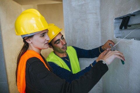 Male and female electrician working on conctruction site stock photo