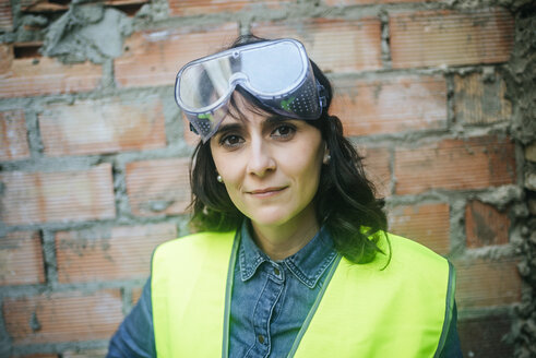 Porträt einer selbstbewussten Frau mit Schutzbrille auf einer Baustelle - KIJF01289