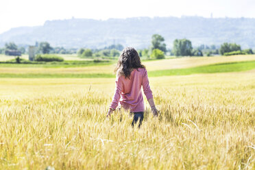 Back view of young woman standing in grain field - SIPF01424