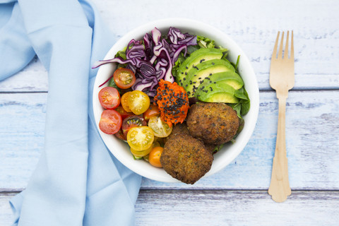 Lunch bowls of leaf salad, red cabbage, avocado, tomatoes, quinoa fritters and ajvar stock photo