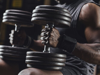 Sportler beim Training mit Hanteln im Fitnessstudio, Nahaufnahme - MADF01368