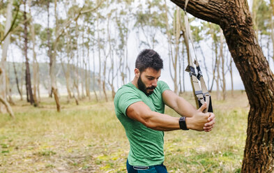 Man doing suspension traning outdoors - MGOF03005