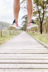 Legs of an athlete jumping on boardwalk - MGOF03011