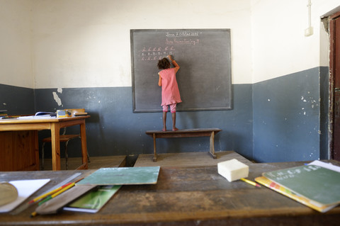 Madagaskar, Fianarantsoa, Schulmädchen schreibt an Tafel, lizenzfreies Stockfoto