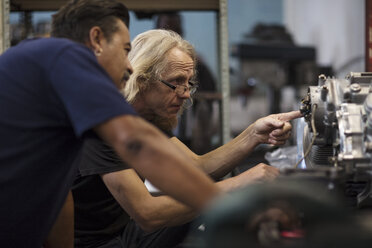 Two mechanics working on motorcycle engine in workshop - ZEF13010