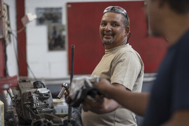 Two mechanics working on motorcycle engine in workshop - ZEF13021