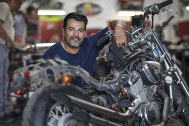 Portrait of smiling mechanic in motorcycle workshop - ZEF13027