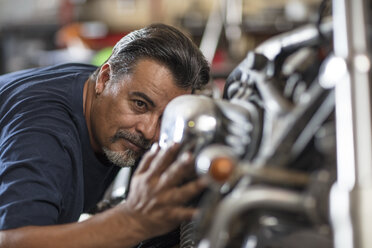 Mechanic examining motorcycle in workshop - ZEF13029