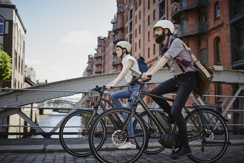 Deutschland, Hamburg, Paar auf Elektrofahrrädern in der Alten Speicherstadt, lizenzfreies Stockfoto