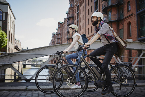 Germany, Hamburg, couple riding electric bicycles at Old Warehouse District - RORF00641