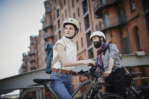 Germany, Hamburg, Old Warehouse District, couple with electric bicycles wat ching something stock photo