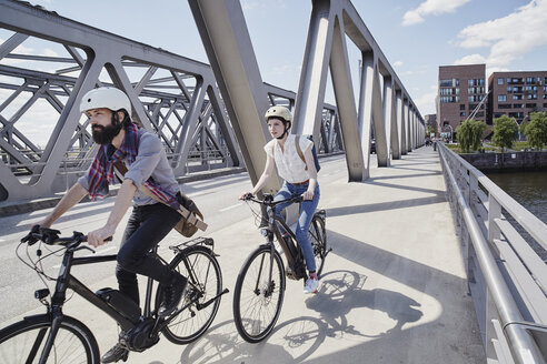 Germany, Hamburg, couple riding electric bicycles on a bridge - RORF00645