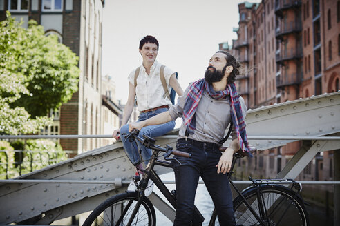 Germany, Hamburg, couple with electric bicycle on a bridge - RORF00648