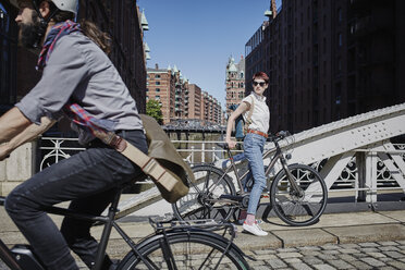 Deutschland, Hamburg, Frau mit Elektrofahrrad beobachtet vorbeifahrenden Mann auf Fahrrad - RORF00651