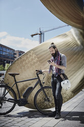 Mann mit Elektrofahrrad schaut auf sein Handy - RORF00659