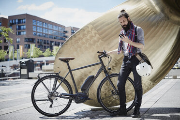 Mann mit Elektrofahrrad schaut auf sein Handy - RORF00660