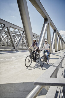 Germany, Hamburg, couple riding electric bicycles on a bridge - RORF00662