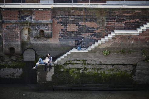 Germany, Hamburg, couple with electric bicycle relaxing at Old Warehouse District - RORF00668
