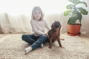 Kleines Mädchen sitzt mit ihrem Hund auf dem Teppich zu Hause - RTBF00699