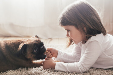 Kleines Mädchen auf dem Teppich liegend mit ihrem Hund zu Hause - RTBF00702