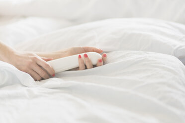 Hand der Frau hält Sexspielzeug im Bett - CHPF00368