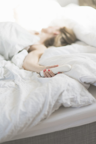 Woman in bed holding sex toy stock photo