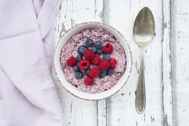 Schüssel mit Overnight Oats mit Blaubeeren und Himbeeren auf Holz - LVF05903