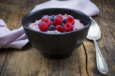 Bowl of overnight oats with blueberries and raspberries on wood - LVF05908