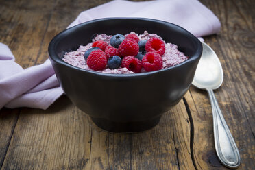 Schüssel mit Overnight Oats mit Blaubeeren und Himbeeren auf Holz - LVF05908