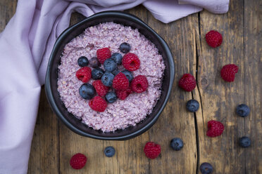 Schüssel mit Overnight Oats mit Blaubeeren und Himbeeren auf Holz - LVF05909