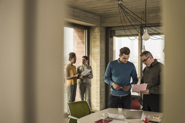 Business man showing document to colleague in office - UUF09987