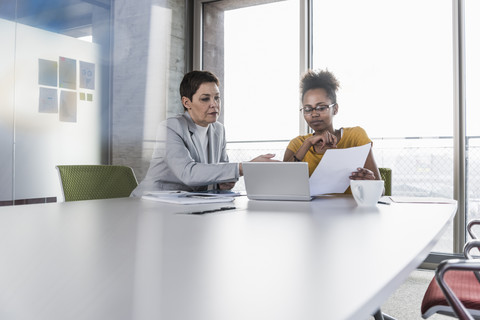 Two businesswomen discussing in conference room stock photo