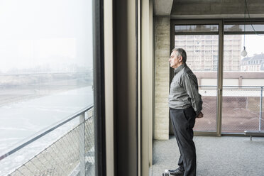 Älterer Geschäftsmann schaut aus dem Fenster - UUF09995