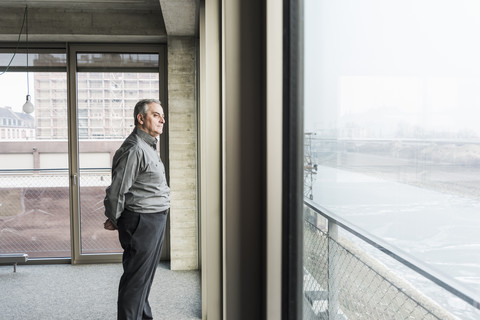 Älterer Geschäftsmann schaut aus dem Fenster, lizenzfreies Stockfoto