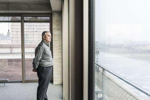 Älterer Geschäftsmann schaut aus dem Fenster - UUF09996