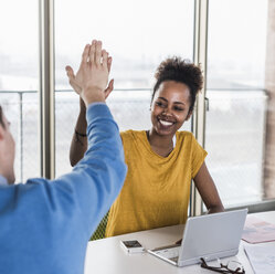 Happy young woman high fiving with colleague in office - UUF10010