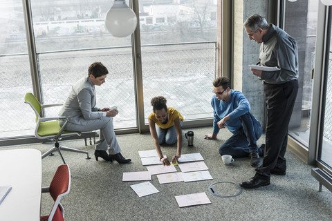 Businesspeople looking at documents on office floor stock photo